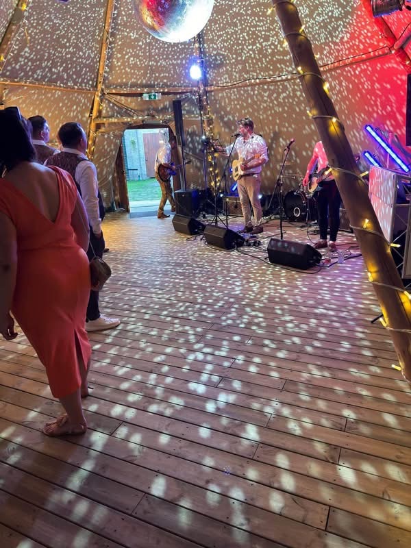 Live band performing in a tipi wedding with mirrorball and fairy light dressing
