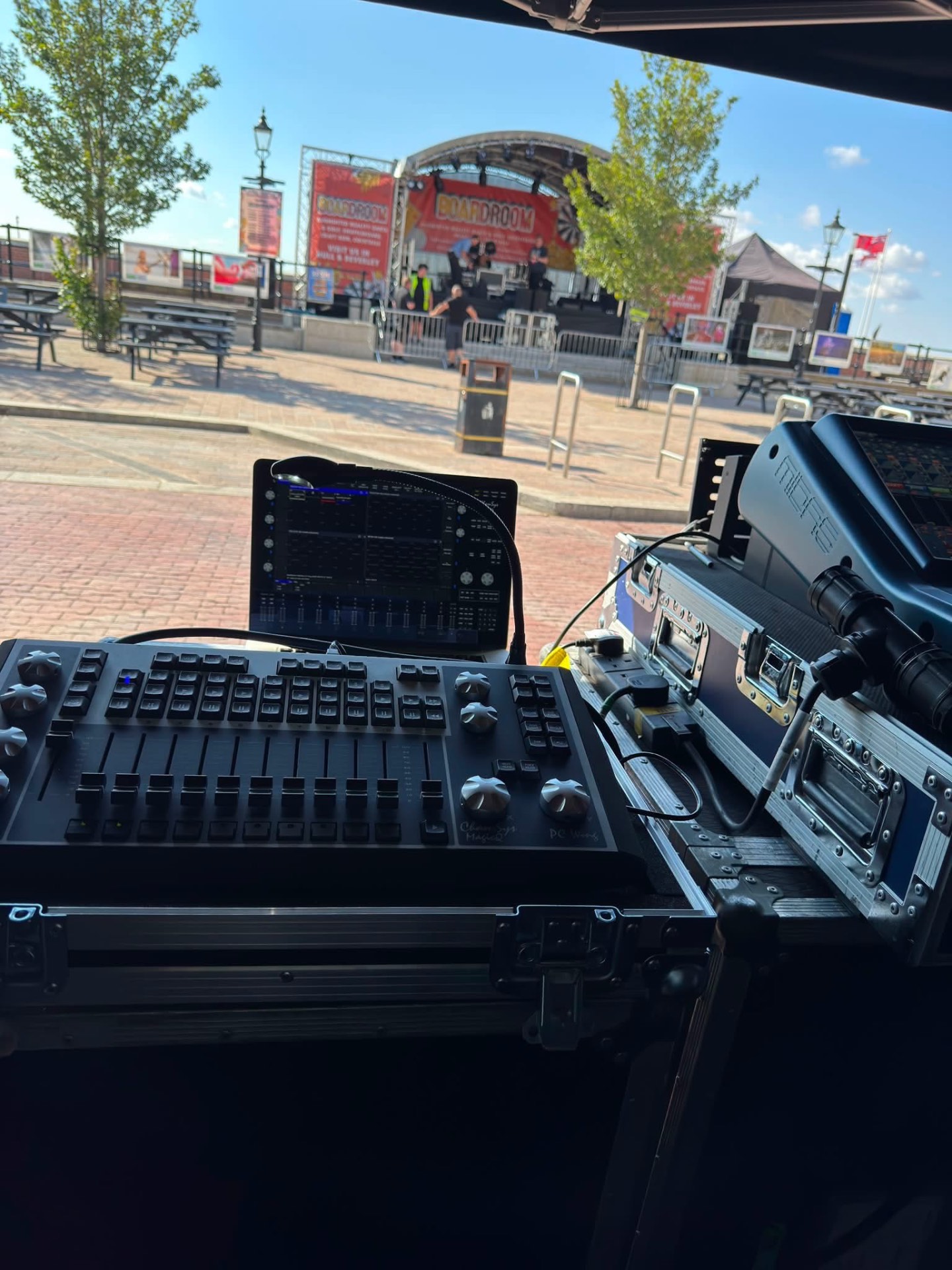 ChamSys MagicQ lighting console and control rack at front of house facing an outdoor festival stage